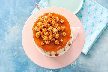Tasty cake with popcorn and caramel on color background