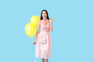 Beautiful young woman with balloons on color background