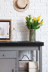 Bouquet of spring flowers on chest of drawers in modern hall