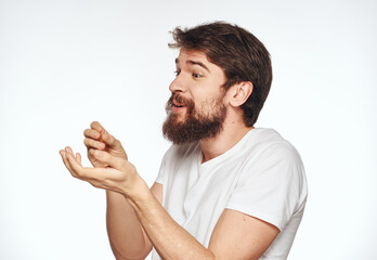 Emotional man with a beard holds his hands near his face on a light background cropped view