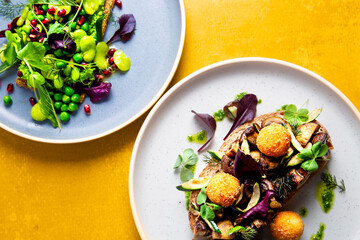 Two plates of healthy restaurant meals. Tasty food on yellow background 