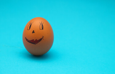 Chicken eggs with painted faces on a blue background. The concept of the Easter holiday.