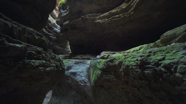 Mystical dark gorge, underground mountain glacial river among ancient rocks covered with green moss and lichen. Abstract tropical nature landscape. Uncharted hard-to-reach places. Gimbal climb. Stock
