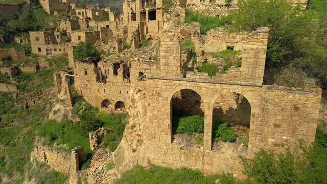 Archaeological ruins of an old abandoned ancient aul on top of Caucasus mountain Dagestan. Amazing Russia ancient stone village. City of dead. Unique travel tourism landmark. Forward flight. Stock 