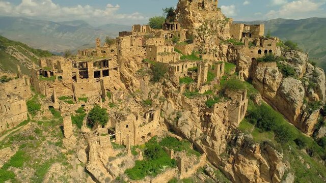 Epic flight orbit old Fortress city Gamsutl ancient settlement on top of mountain, stone ruins aul Caucasus Dagestan. Unique mystical architecture Russia. Dramatic clouds. Ancient civilization. 4k