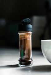 Instant coffee powder in a small glass bottle and white bowl to whisk into foam, Dalgona coffee preparation time in home kitchen.