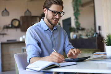 Happy young business man is analizing financial documents from home during self isolation.