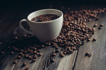 fragrant coffee beans on a wooden table and a cup with a hot drink on a saucer