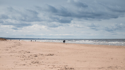 Fototapeta na wymiar View of the seashore and people walking in a cloudy stormy day. 16x9