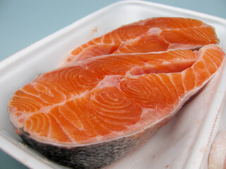 Two pieces of raw fresh salmon steak in a food container