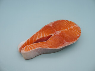 One piece of raw fresh salmon steak on a blue background
