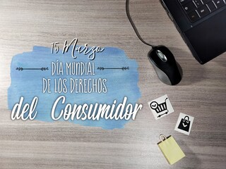 World Consumer Rights Day written in Spanish. notebook, mouse and shopping cart on wooden table....