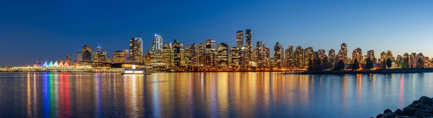 Obraz premium Night view of Vancouver downtown skyline panorama after sunset. Colorful buildings lights reflections on waterfront harbor. British Columbia, Canada.