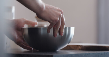 man making granola mix cereal flakes in steel bowl on kitchen countertop