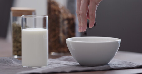 serving chocolate granola pour in white bowl on walnut table