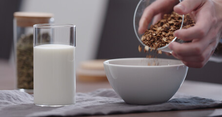 serving chocolate granola pour in white bowl on walnut table