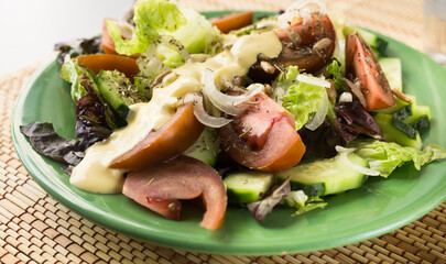 vegetable salad of greens, tomatoes and cucumbers on a green plate