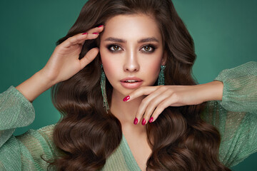 Fototapeta premium Brunette girl with perfect makeup. Smiling beautiful model woman with long curly hairstyle. Care and beauty hair products. Red nails manicure