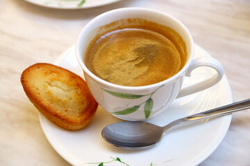 Cup of Hot Coffee with a Financier French Almond Mini Cake on White Table	