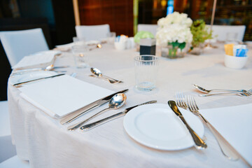 Elegant tables set up for banquet, Empty glasses, cutlery set knife, spoon, fork, napkin and bouquet in restaurant