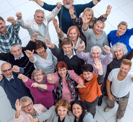 group of happy elderly people standing with their hands up .