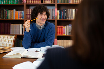 photo of a guy scientist who sits in the library, working on a project and smiling. Student science. High quality photo