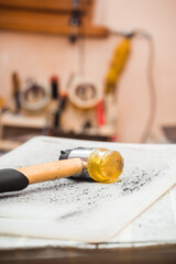 The hammer lies on a gray table with holes from blows