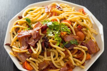Spaghetti alla Amatriciana with bacon, tomatoes and dried chili on black wood table.