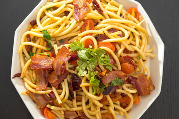 Spaghetti alla Amatriciana with bacon, tomatoes and dried chili on black wood table.