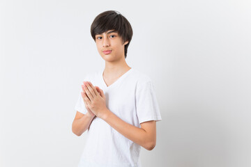 Smiling teen boy greeting with palms gesture pressed together on white background.