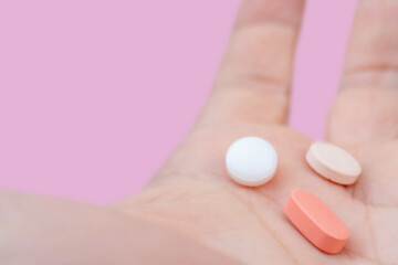 White and pink pills in the palm of your hand. Treatment with pills.
