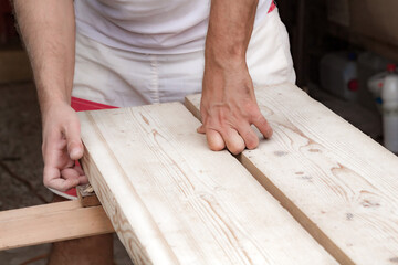 Male carpenter working with wood material in a garage.