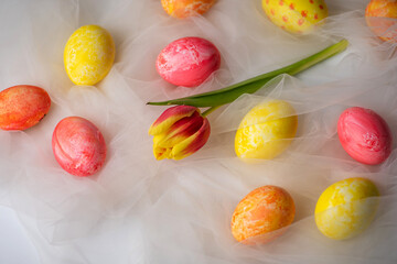 Painted Easter eggs with fresh tulips on white fabric