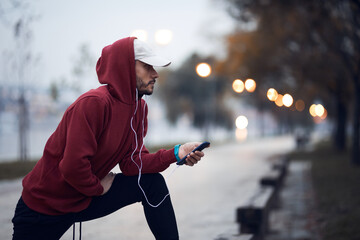 Athletic sporty man training in hoodie sweatshirt in urban city park.