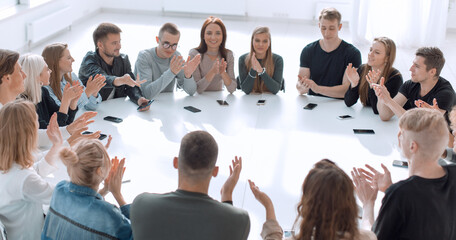 group of young people applauding, sitting at a round table