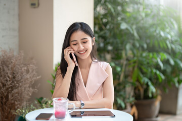 Beautiful Asian woman talking on the phone at coffee shop.