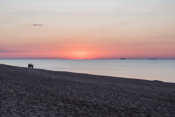 Fototapeta na wymiar view of sunrise above sandy sea beach. ships on horizon