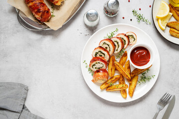 Bacon wrapped chicken rolls stuffed with feta cheese and spinach served with baked potato wedges...
