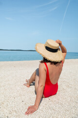 sexy woman in red swimsuit sitting at a beach