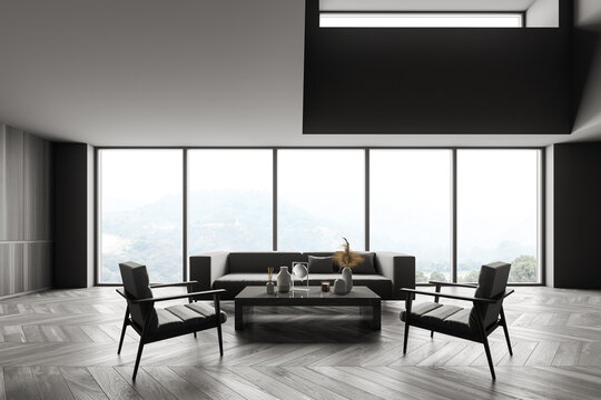 Dark living room with sofa and armchairs near panoramic windows