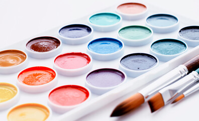 Watercolour paints and a palette on a white background.