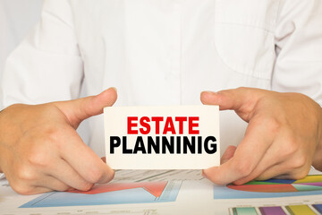 a man in the office holds a card with text ESTATE PLANNING . business concept