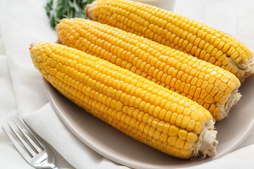 Plate with tasty baked corn cobs on table, closeup