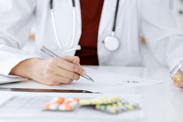 Unknown woman-doctor fills up prescription form. close-up. Panacea and life save, prescribe...