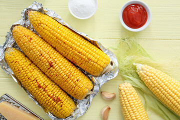 Tasty baked corn cobs on wooden background