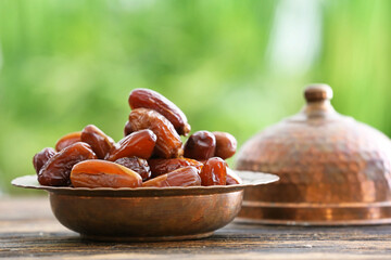 Bowl with sweet dried dates on table against blurred background