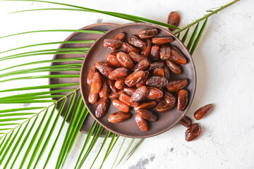 Plate with sweet dried dates on light background