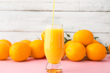 Glass of orange juice on light wooden background