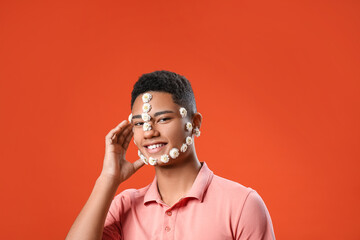 Portrait of handsome young man with flowers on face against color background