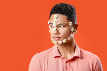 Portrait of handsome young man with flowers on face against color background